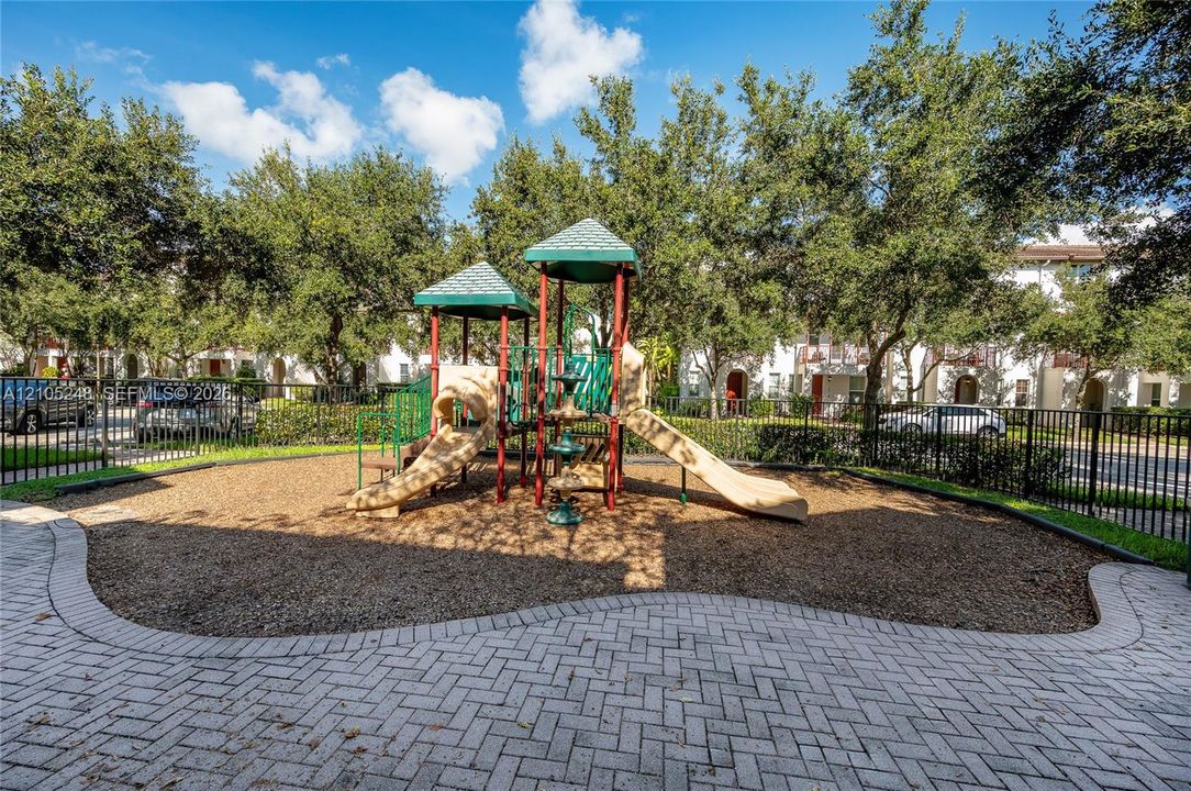 Outdoor play structure with slides and climbing elements, surrounded by wood chip surfacing
