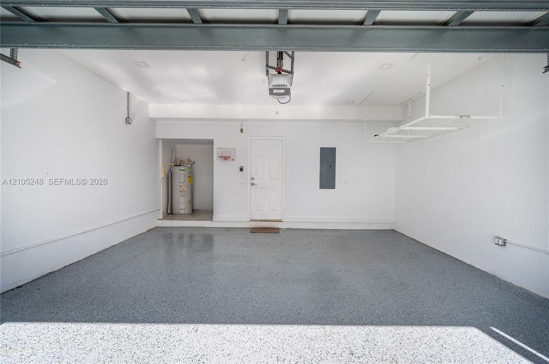 Garage with epoxy-coated flooring, overhead storage racks, and a built-in water heater closet