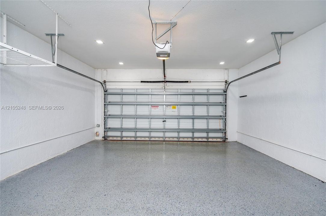 Attached garage featuring a textured concrete floor, recessed ceiling lighting, and a garage door opener
