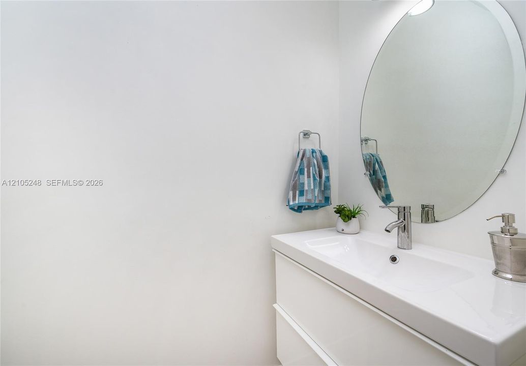 White floating vanity with integrated sink, chrome faucet, and oval wall mirror