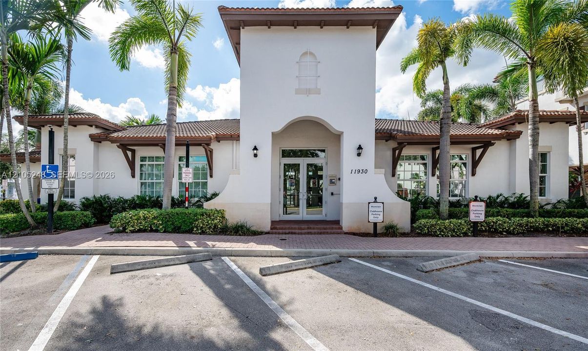 Spanish Colonial architecture with a prominent arched entry, terracotta tile roofing, and well-maintained landscaping