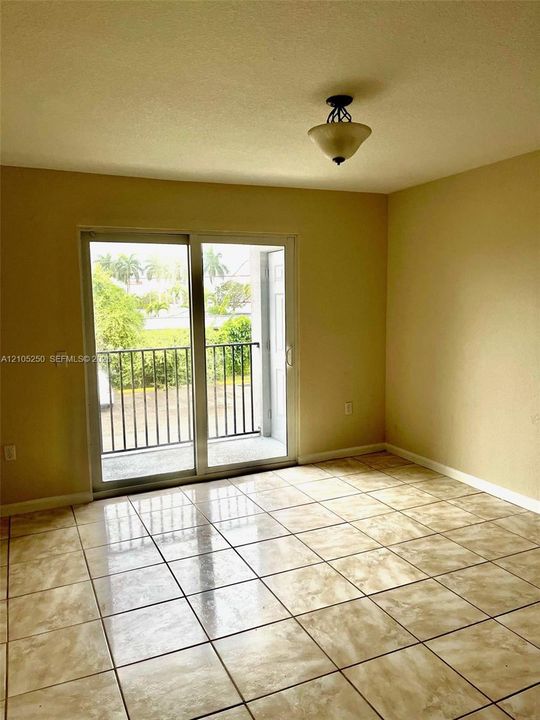 Tiled flooring throughout, sliding glass door leading to a private balcony, and a mounted ceiling light fixture