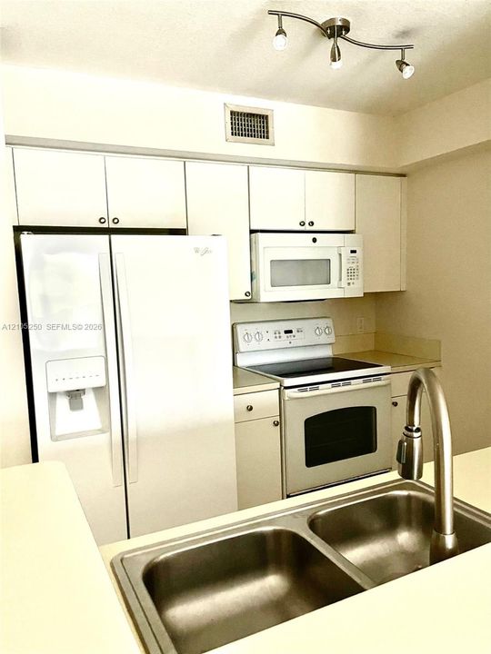 Kitchen featuring white cabinetry, a double basin stainless steel sink, a stainless steel faucet, and track lighting