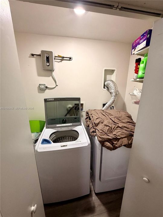 Dedicated laundry area with wood-finish flooring and built-in shelving