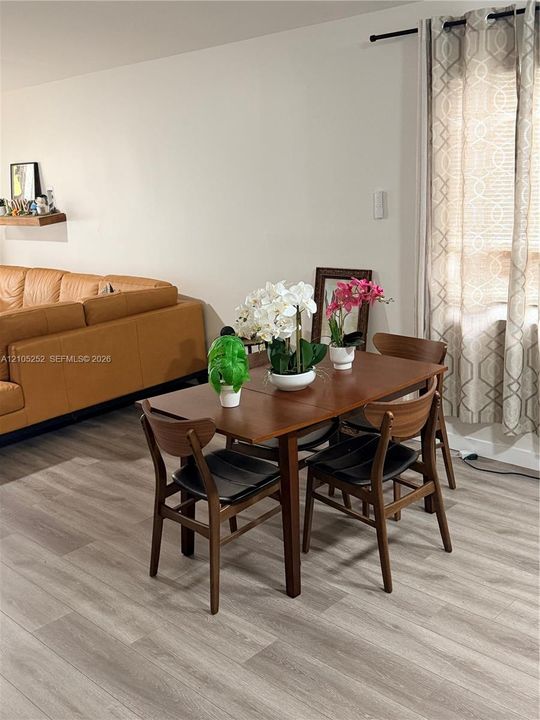 Wood-finish flooring throughout, light-toned walls, and a window with curtains