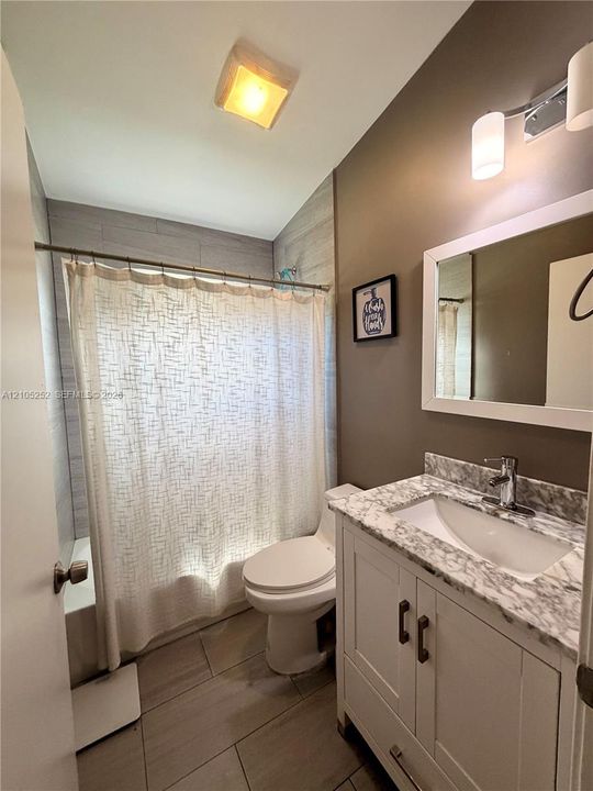White vanity with double-door cabinetry, integrated sink, and stone-finish countertop