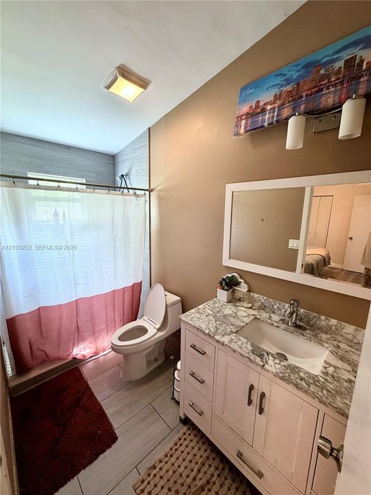 Vanity with integrated sink and marble-look countertop, white framed mirror, and rectangular floor tiles