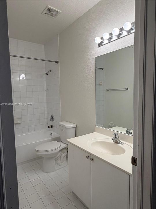 White subway tile shower surround with a built-in tub, white tile flooring, vanity with an integrated sink, and a mirrored medicine cabinet