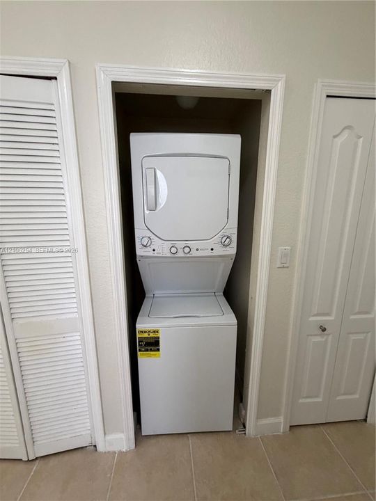 Stackable washer and dryer unit, louvered closet doors, and tiled flooring