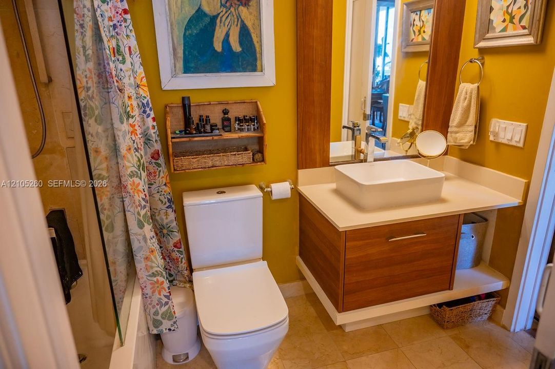 Wall-mounted vanity with wood-finish cabinetry, rectangular vessel sink, and an integrated countertop