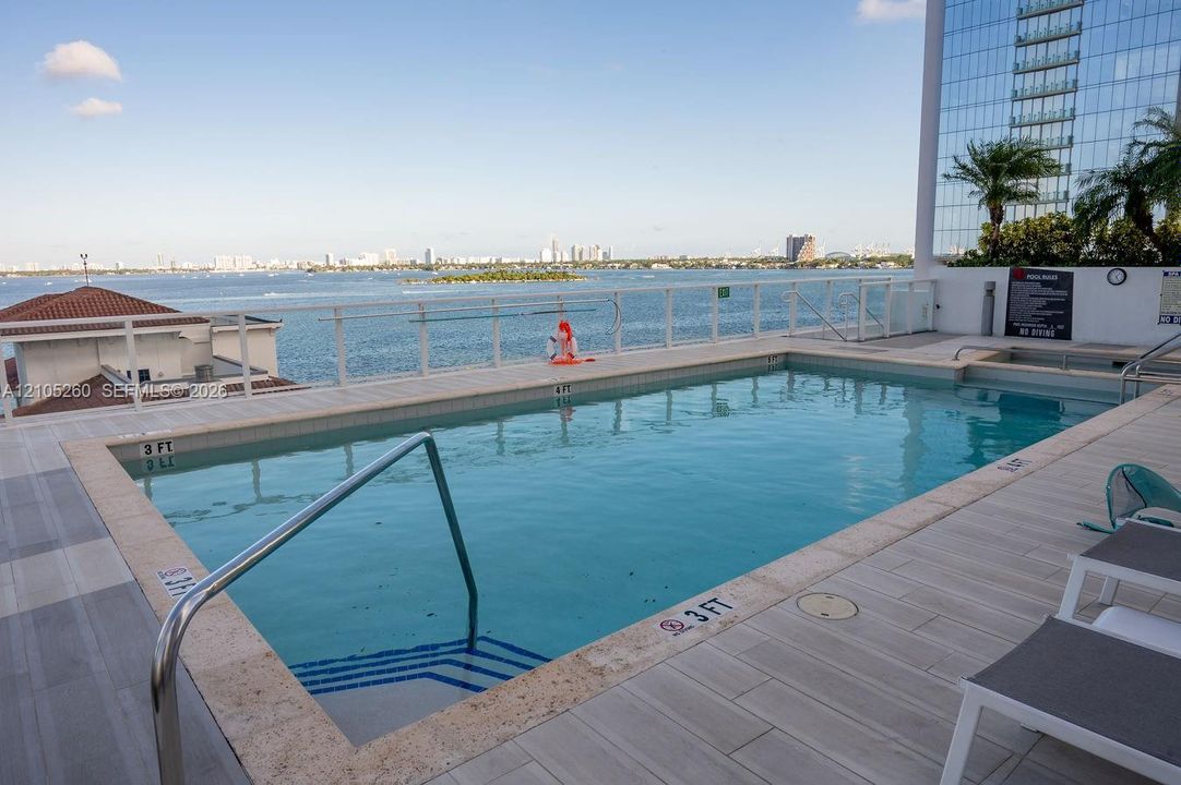 Rooftop pool with water scenery, integrated spa, and tile surround