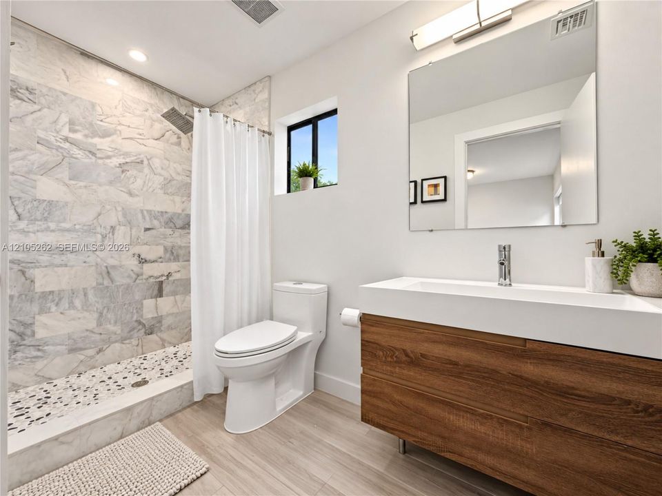 Modern bathroom with a wood-finish vanity, integrated rectangular sink, and chrome fixtures