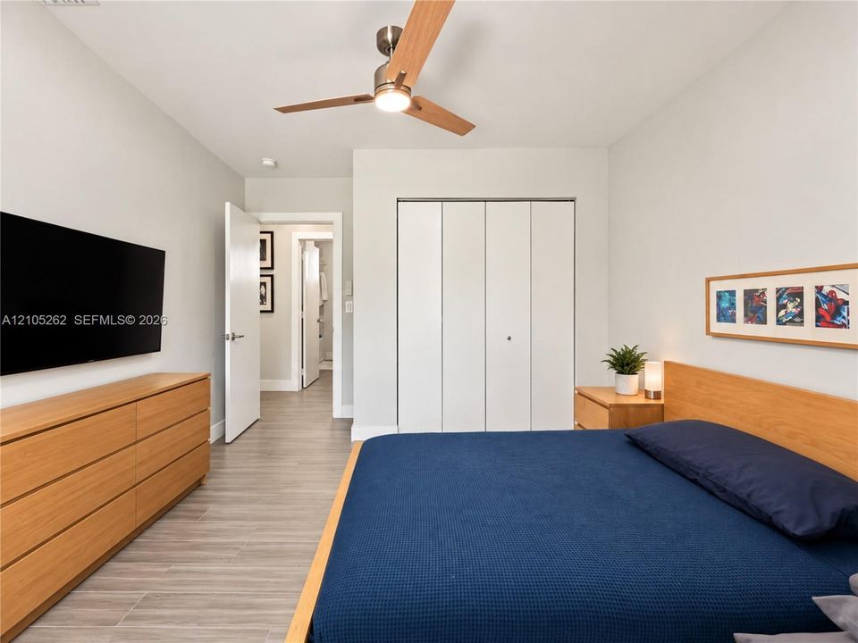 Light wood-finish flooring with a ceiling fan featuring a light fixture, and a built-in closet with bi-fold doors