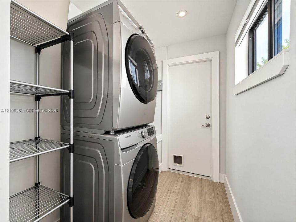 Stackable laundry appliances, recessed ceiling lighting, light wood-finish flooring, and a framed window