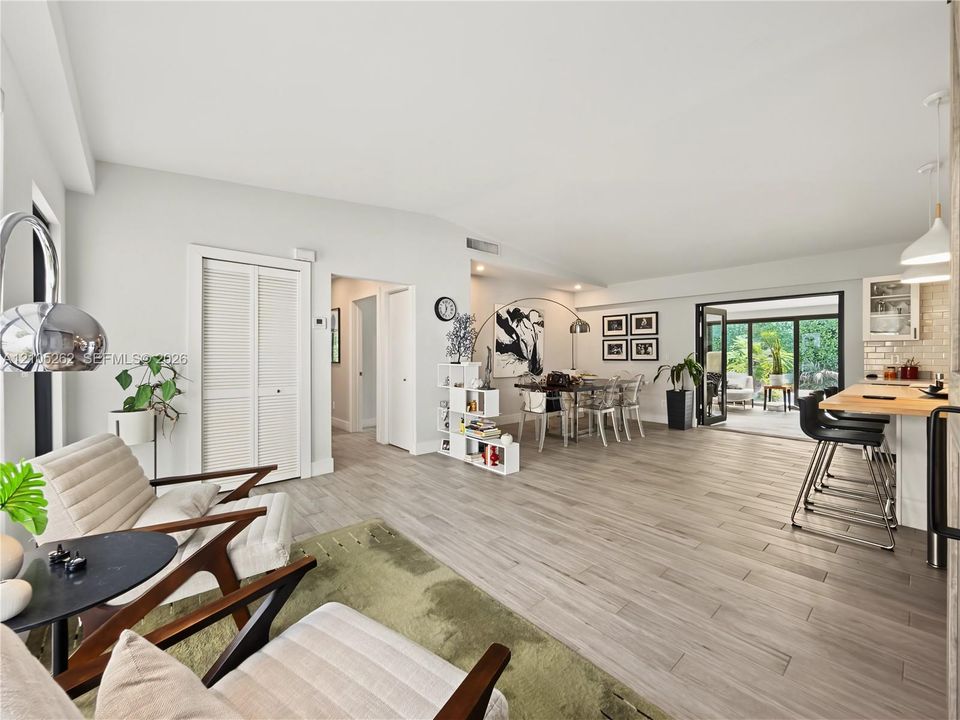 Wood-finish flooring throughout, integrated kitchen island with breakfast bar, bi-fold patio doors, and a vaulted ceiling