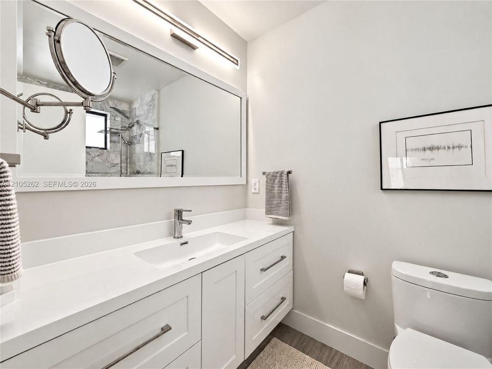 Vanity with an integrated rectangular sink, sleek chrome faucet, and expansive wall mirror