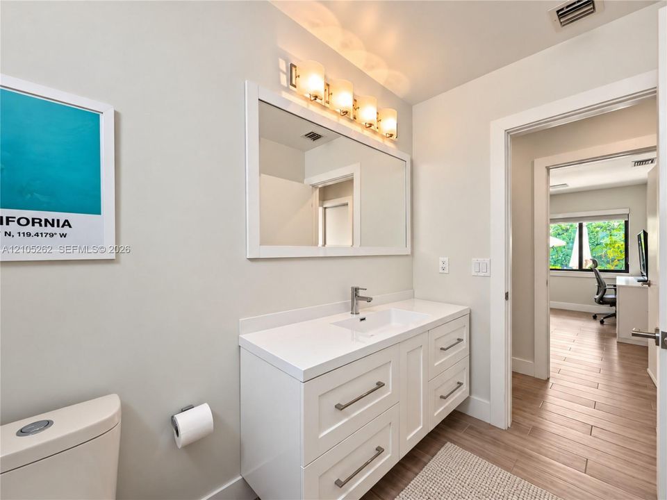 White vanity with ample storage drawers, sleek countertop, and integrated sink