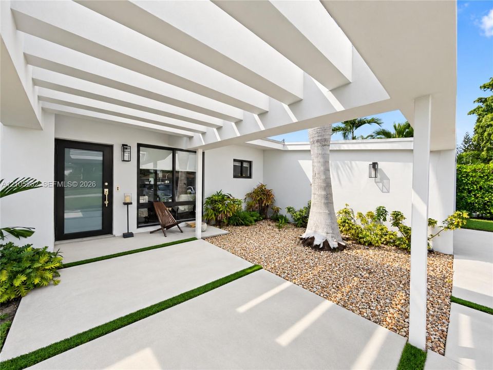 Modern exterior architecture featuring a white pergola, dark-framed entry door, and large windows