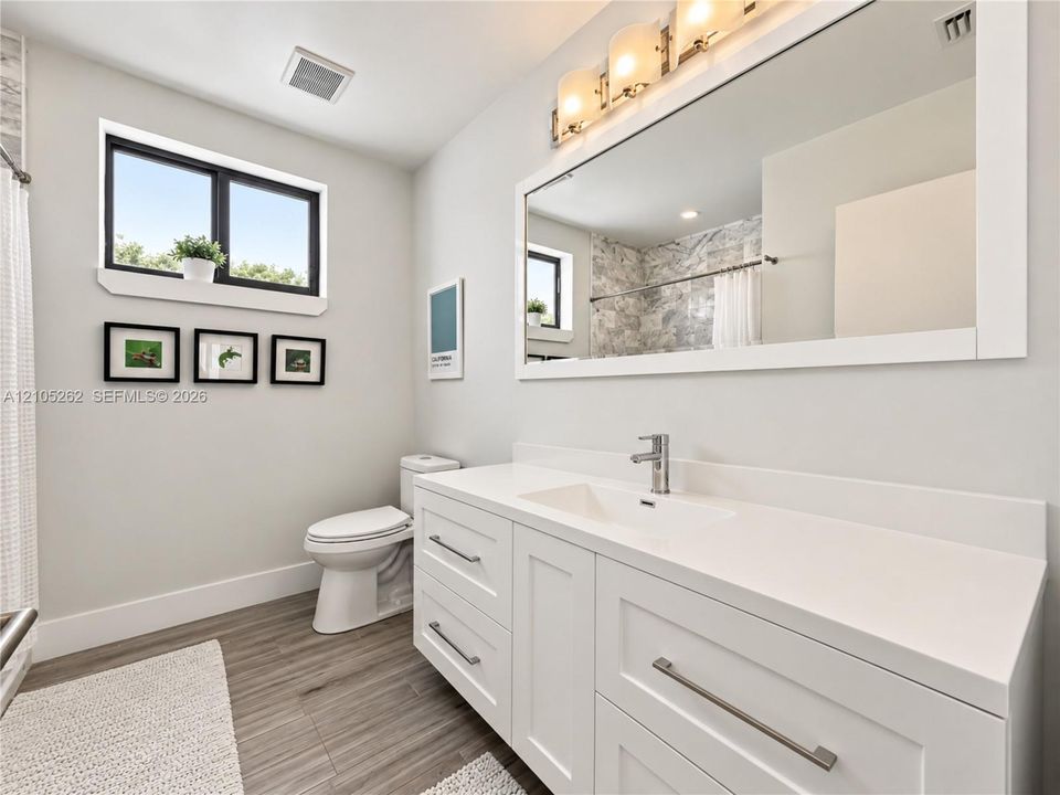 White vanity with integrated sink, chrome faucet, and rectangular mirror