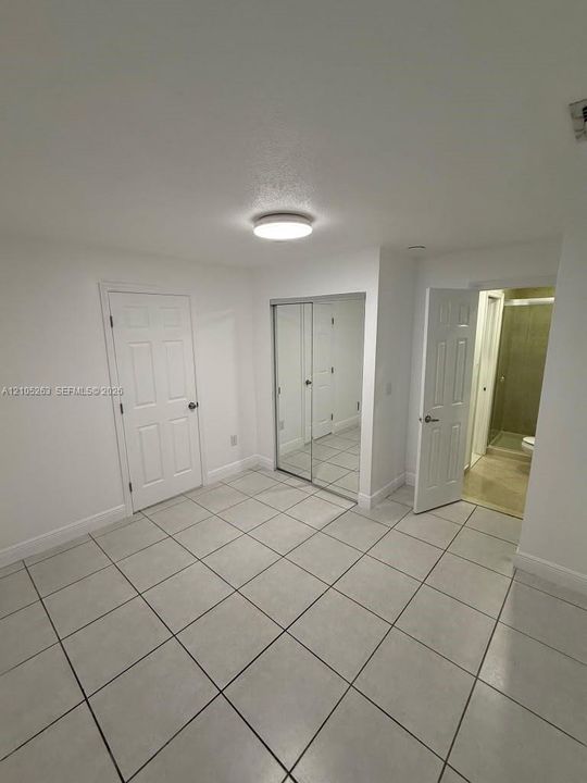 White tiled flooring, mirrored closet doors, and recessed ceiling lighting