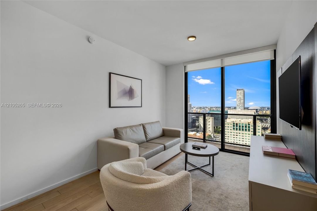 Floor-to-ceiling windows, wood-finish flooring, and built-in vertical slat paneling