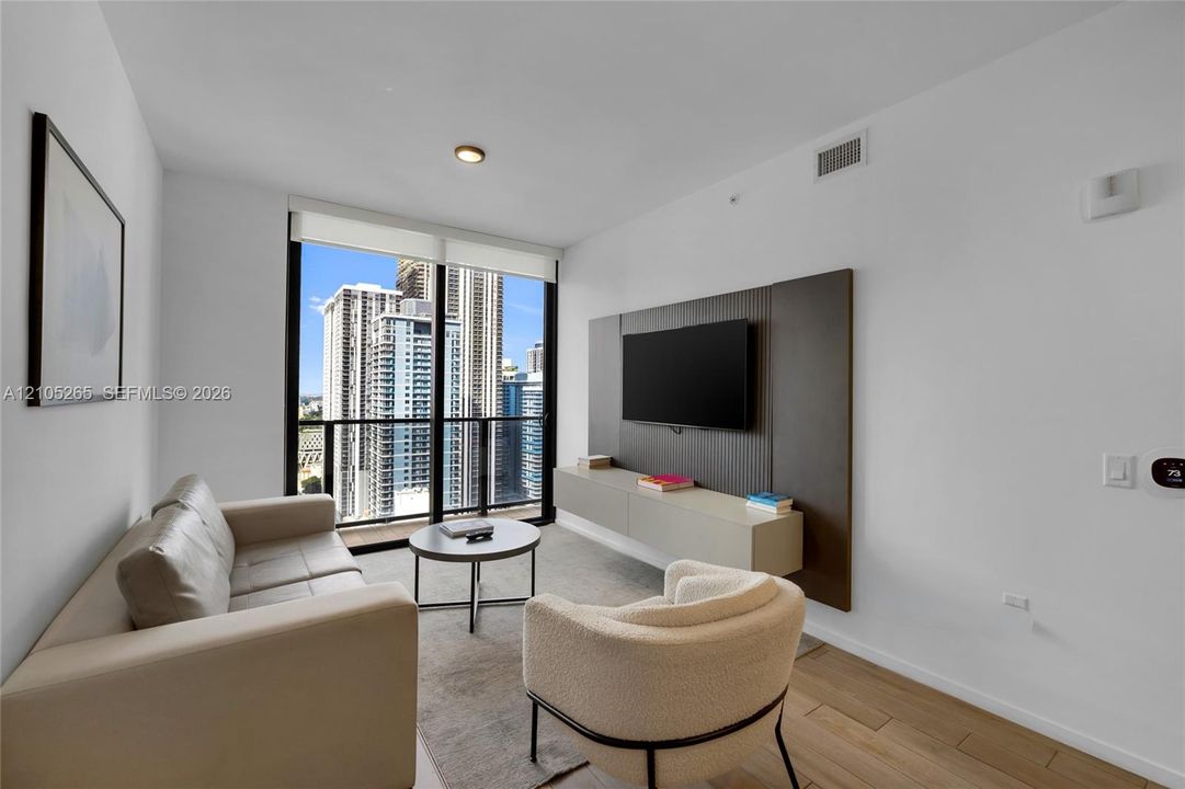 Floor-to-ceiling windows, wood-finish flooring, custom wall paneling, and a wall-mounted floating cabinet
