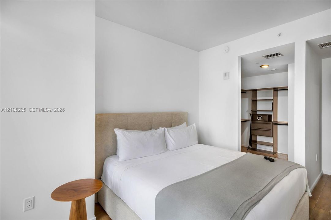 Neutral-toned upholstered headboard with recessed lighting and walk-in closet featuring integrated shelving