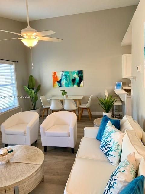 Vaulted ceiling with an attached ceiling fan, wood-finish flooring, and white window blinds