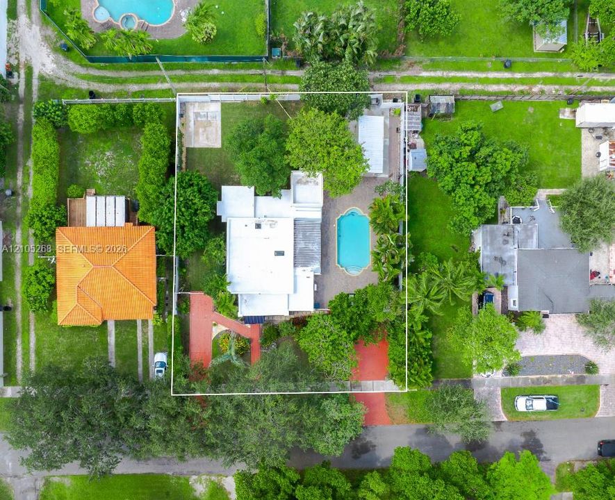 Aerial perspective showcasing a property with a swimming pool, mature landscaping, and a substantial lot size