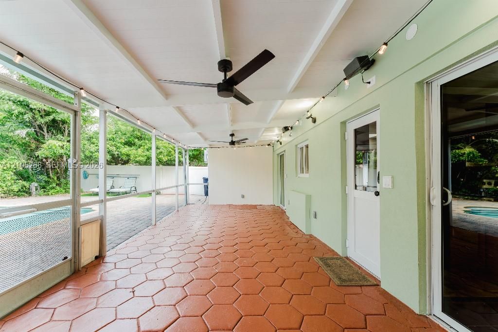 Screened patio featuring hexagonal paver flooring, two ceiling fans, and string lighting