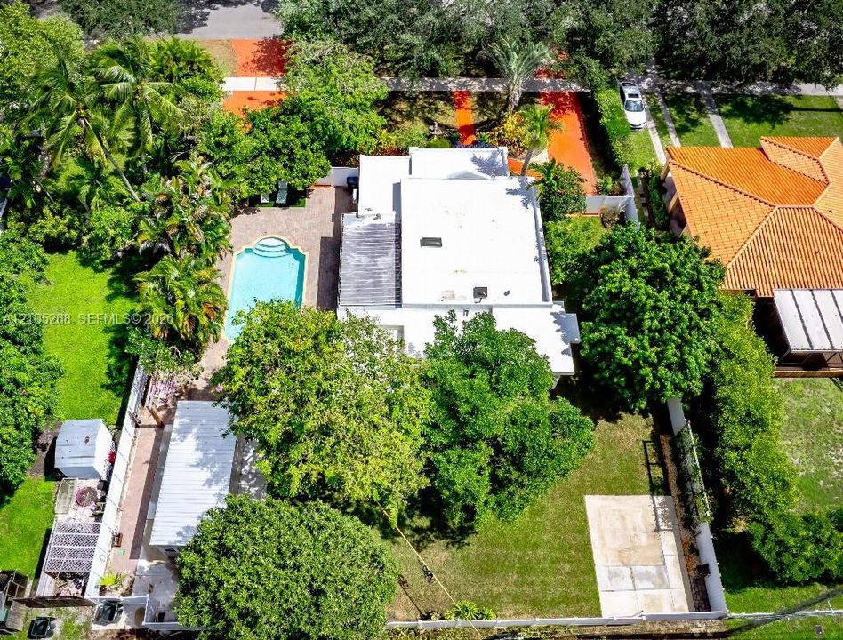 Rectangular residence with a flat roof, surrounded by mature trees and lush landscaping