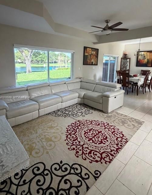 Tray ceiling, large picture windows, ceiling fan with integrated lighting, tile flooring, and sliding glass doors