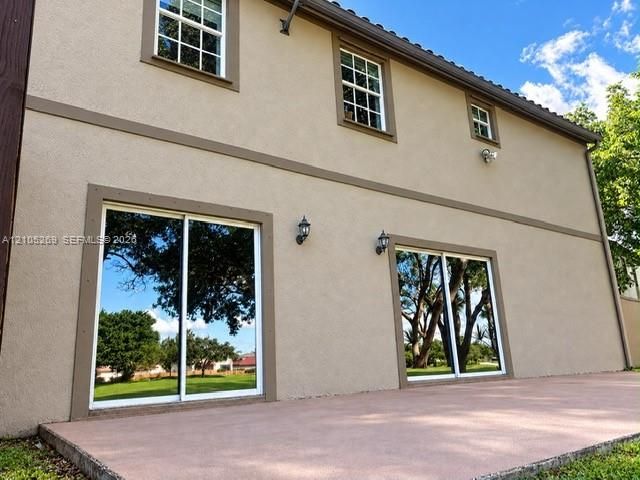 Expansive concrete patio with two sliding glass doors and two wall-mounted exterior lights