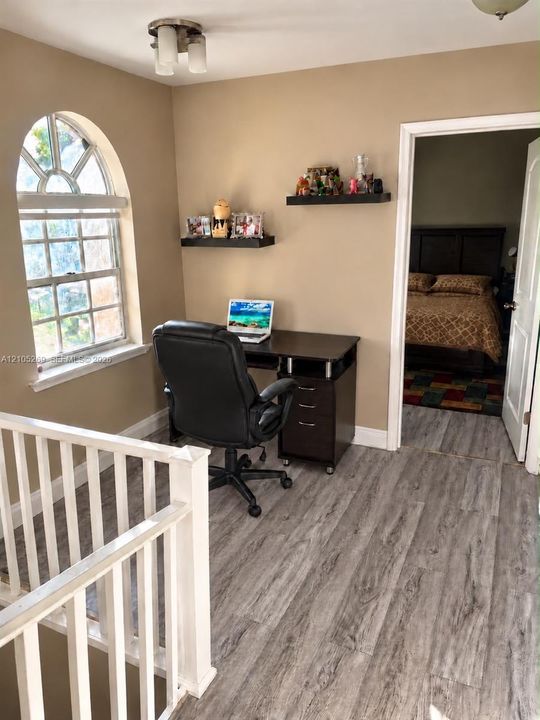 Arched window, wood-finish flooring, ceiling-mounted light fixture, and white railings