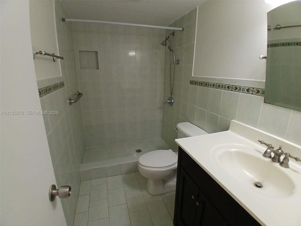 Tiled shower with a built-in niche, chrome shower fixtures, and a grab bar