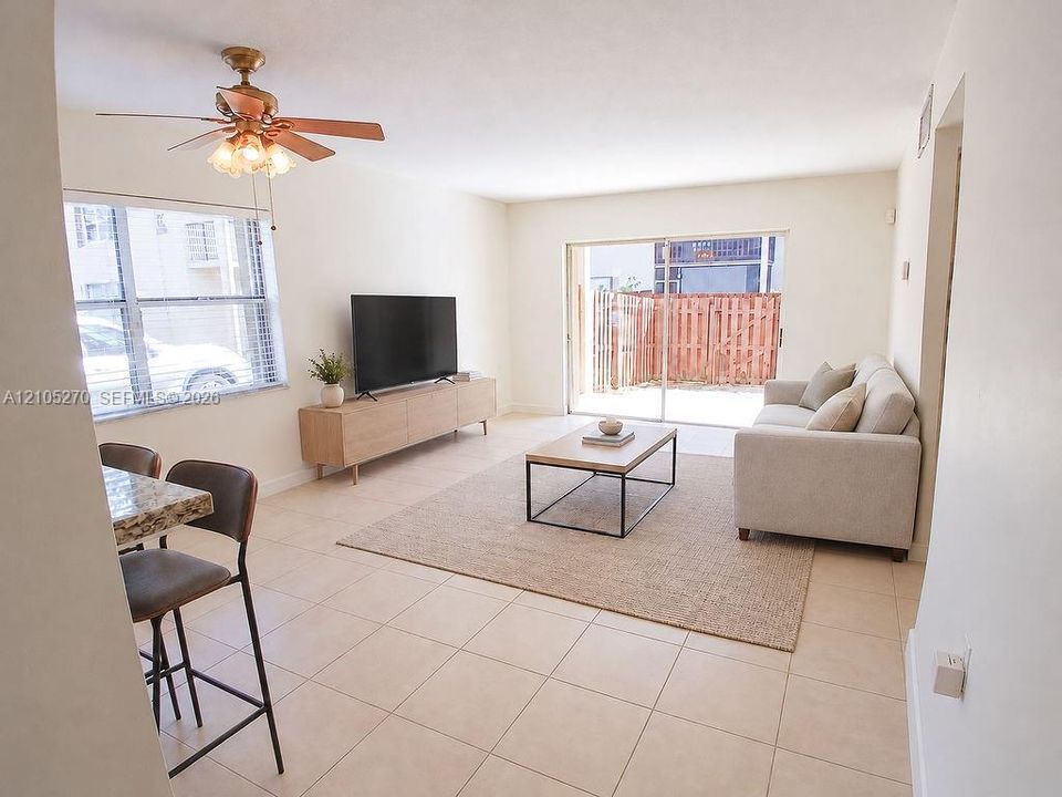 Tiled flooring throughout, sliding glass door to outdoor space, ceiling fan with light fixture, and window with blinds