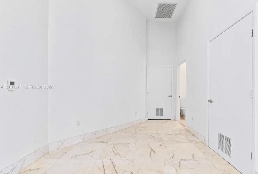 High-ceiling interior featuring polished stone tile flooring and stone tile wainscoting