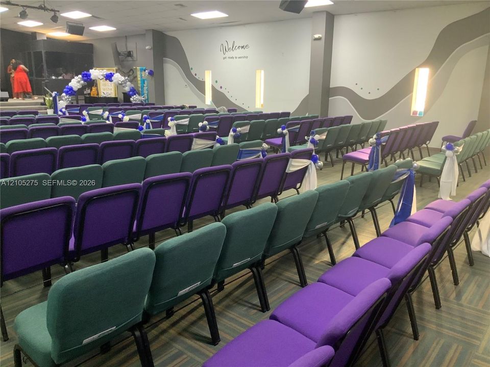 Spacious hall with patterned wall accents, recessed lighting, and a raised platform