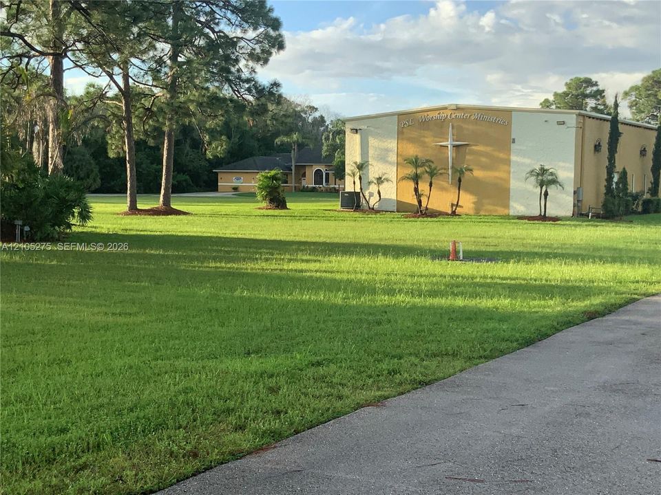 Expansive grassy area with mature trees and a paved drive