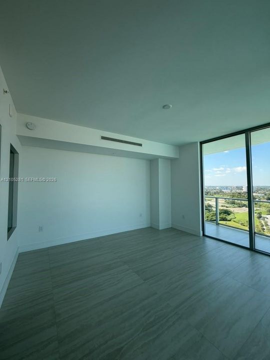 Floor-to-ceiling glass sliding doors, private balcony, wood-finish tile flooring, recessed ceiling HVAC, and neutral wall finishes