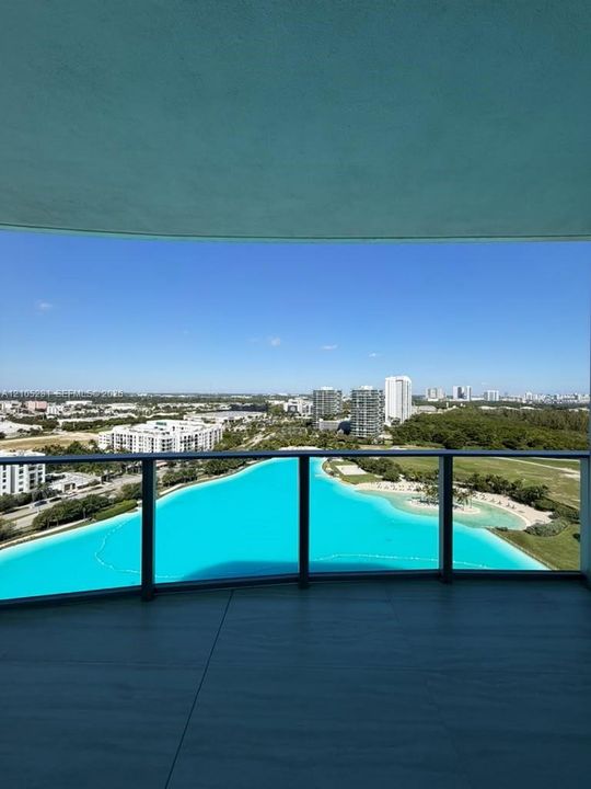 Covered balcony featuring large-format tile flooring and a glass railing
