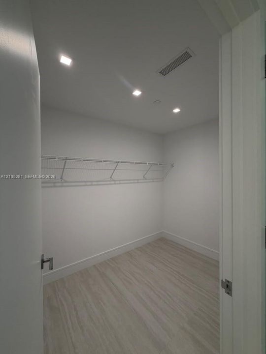 Storage space featuring wood-finish flooring, recessed lighting, and wall-mounted wire shelving
