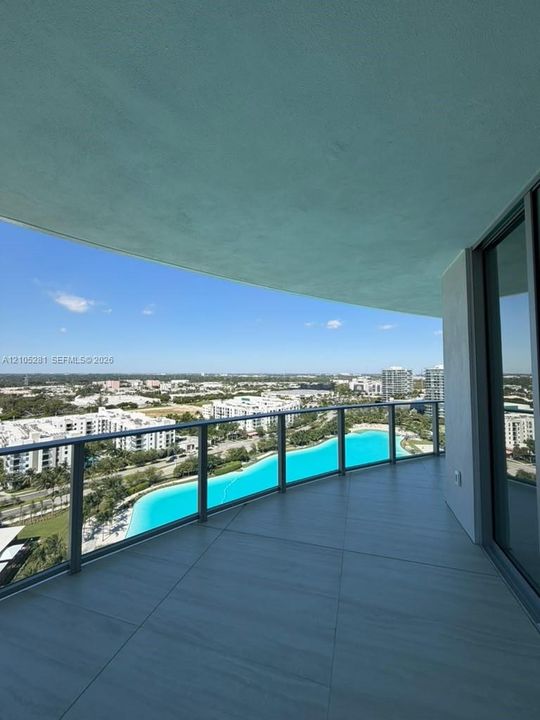 Covered balcony featuring large-format porcelain tile flooring and a glass panel railing