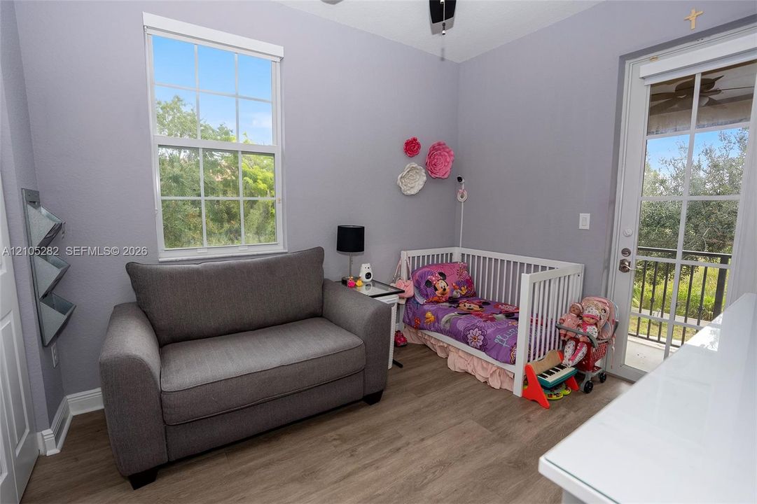 Room featuring wood-finish flooring, a multi-pane window, and a glass-panel door providing exterior access