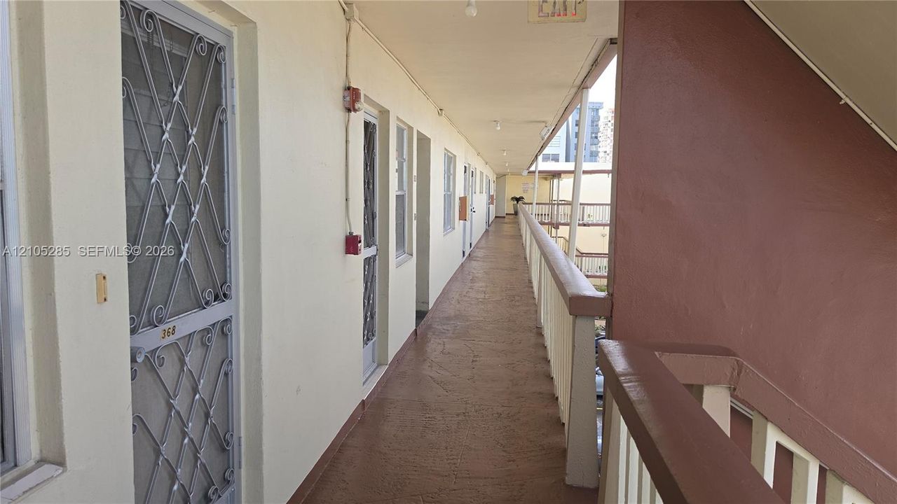 Exterior covered walkway featuring decorative metal security screen doors and a painted handrail