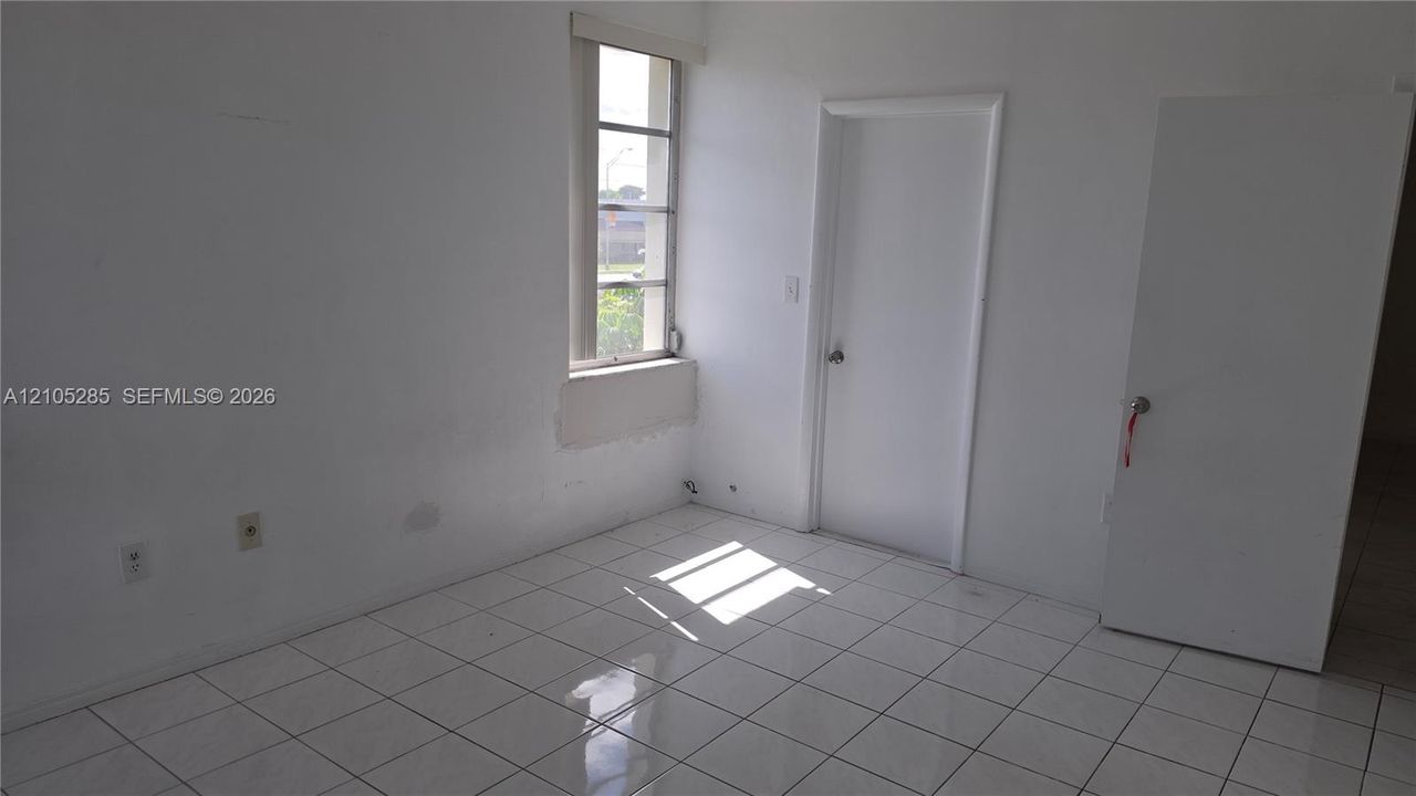 Interior space featuring light-colored tile flooring, white-painted walls, and a single-pane window