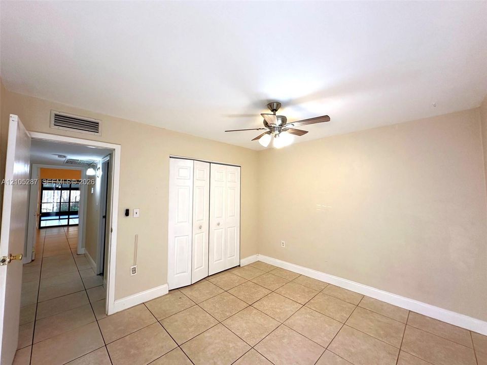 Ceiling fan with integrated lighting, tile flooring, bi-fold closet doors, and light-toned walls