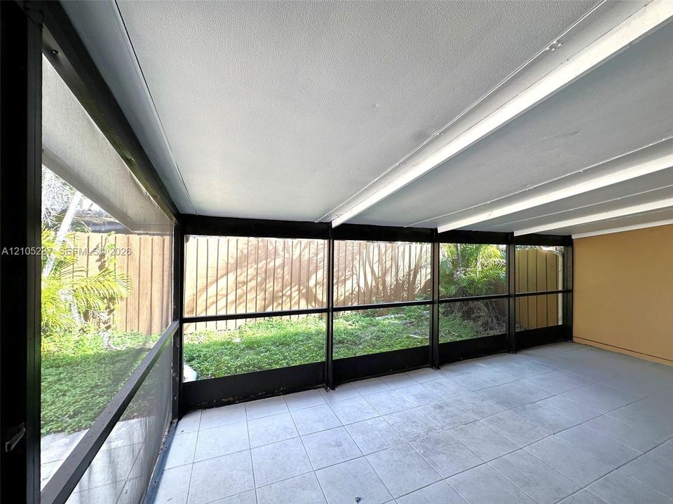 Screened-in patio featuring tiled flooring, a textured ceiling, and a solid perimeter fence
