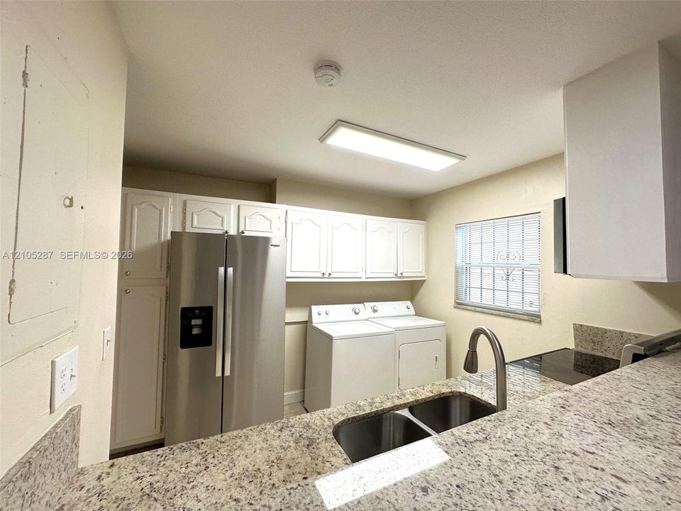 Kitchen with white cabinetry, a double basin sink, and light-toned countertops