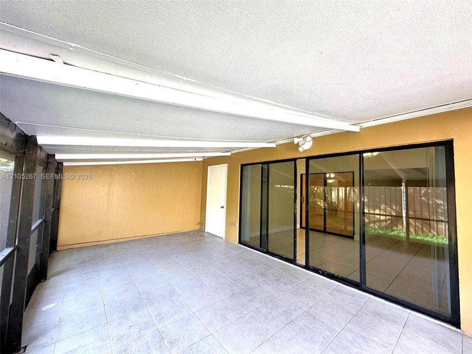 Covered patio with a textured ceiling, tile flooring, and large sliding glass doors